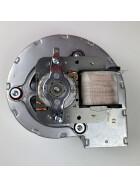 Unteransicht eines MCZ-Luftgebläses mit sichtbarem Motor und Kupferspulen. Das Metallgehäuse ist mit mehreren Schrauben befestigt, und die zentrale Achse des Lüfterrads ist gut erkennbar. Auf der rechten Seite befindet sich eine Spule mit einer Wicklung aus feinem Draht, die zur Erzeugung des Magnetfelds dient.